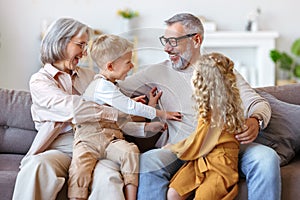 Kids and grandmother tickling grandpa while having fun at home, happy family senior grandparents and children having fun together