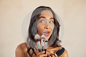 Playful latin woman holding beauty brush with funny expression