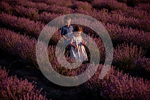 Playful little cute couple boy girl walk on purple lavender flower meadow field background, have fun