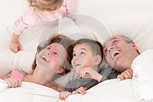 Playful little girl with her family in bed