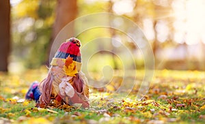 Playful little girl hiding her face behind autumnal leaf in the park.