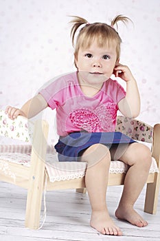 Playful little girl sitting on the small wooden bed