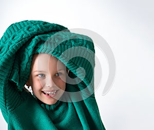 Playful little girl wearing knitted green sweater that is too big for her, raising hands in long sleeves above head