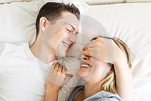 Playful Male Smiling Covering Woman`s Eyes In Bed