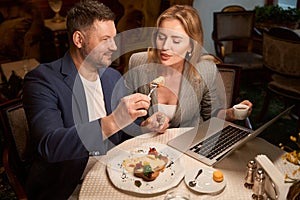 Playful man feeding his girlfriend with tasty lunch, flirt