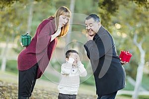 Playful Mixedrace Parents With Gifts for Young Boy Hiding Eyes photo