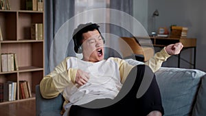 Playful mood. Carefree mature asian man listening to music via headphones and playing imaginary guitar, slow motion