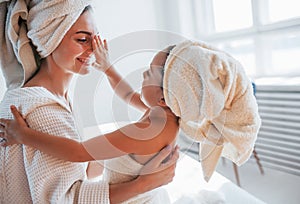 Playful mood. Young mother with her daugher have beauty day indoors in white room