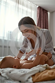 Playful mother with baby boy in light bedroom