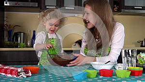 Playful mother with cute child girl tasting chocolate dough from finger and kiss