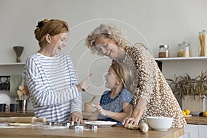 Playful multi-generational family having fun, laughing, enjoy cookery in kitchen photo