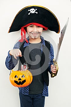 Playful pirate. Shot of a little boy dressed in a pirate costume while holding a jack o lantern against a white