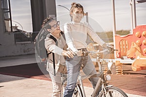 Playful positive couple woman riding bike