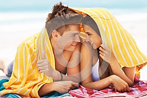 Playful romance. an affectionate young couple smiling at each other while lying with a towel over their heads at the