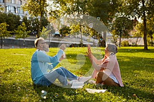 Playful senior couple blowing soap bubbles while rest in park