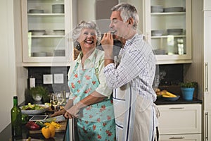 Playful senior couple enjoying while cooking in kitchen