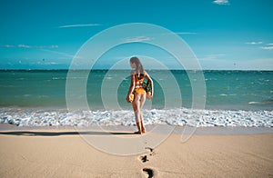 Playful slim woman in sexy bikini stands back walks away hawaii or maldives sea beach holding fresh pineapple. Hot