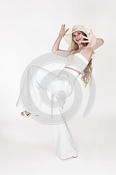 Playful smiling woman standing on one leg with arms raised and looking at camera. Full length shot