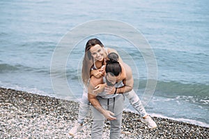 Playful sportive men giving piggyback ride to women on beach.