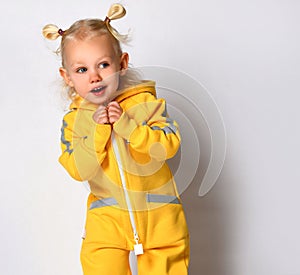 Playful toddler girl dressed in a warm yellow sports jumpsuit.