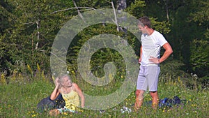 Playful tourist couple having problems setting up their tent by the calm forest.