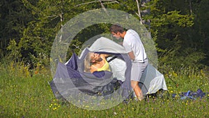 Playful woman gets tangled up in tent while boyfriend tries to prepare campsite.