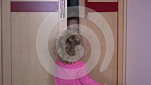 Playful woman hiding from daughter child in wardrobe closet at home