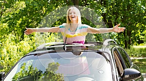 Playful woman standing in a car sunroof