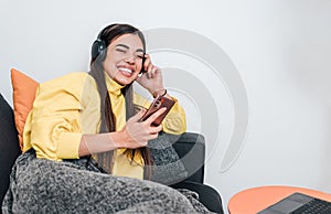 Playful young adult woman, laying in bed, jamming with headphones on