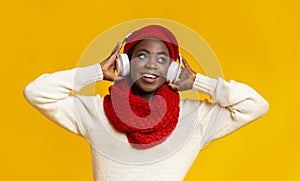 Playful young black girl in headphones listening to music