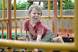 A playful young boy is happily climbing on the playground equipment, enjoying his outdoor adventure under the sunny sky