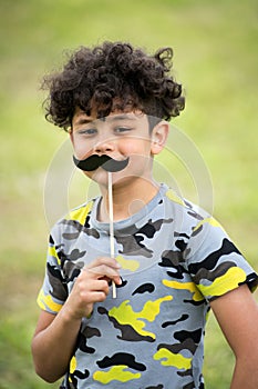 Playful young boy holding up a mustache