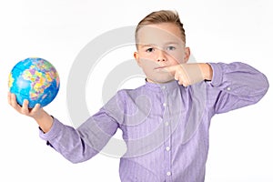 Playful young caucasian school boy holding a globe on white studio background.Boy shows at globe laughing
