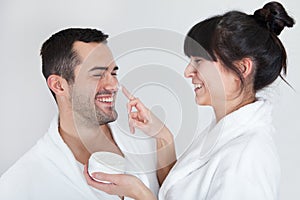 Playful young couple applying cream