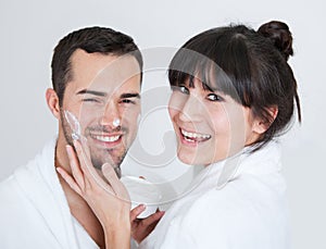 Playful young couple applying cream