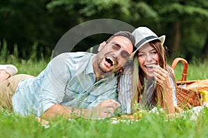 Playful young couple enjoying their time together, having relaxing picnic in a park