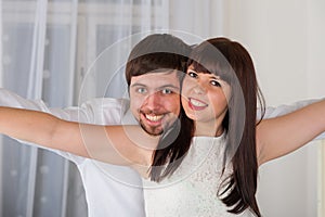 Playful, young couple flying against home interior