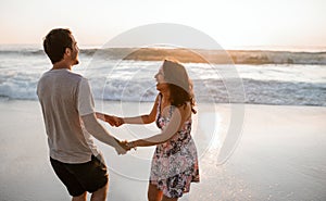 Playful young couple having fun at the beach at sunset