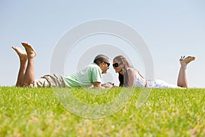 Playful young couple laying on a grass lawn