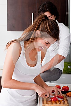 Playful young girlfriend slicing tomatoes