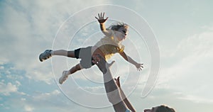 Playful young man tosses his daughter on summertime hike journey to mountain.