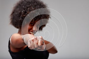 Playful young woman throwing a punch at the camera