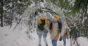 Playful youth walking in winter forest having fun with snowy trees enjoying leisure time together