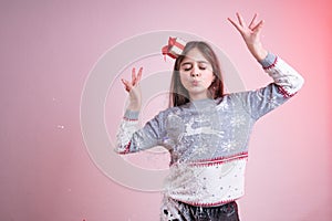 Playfull brunette girl with closed eyes and raised hands, dressed in santa sweater and hat, stained in synthetic snow