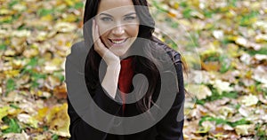 Playfully smiling woman sitting on grass