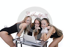 Playgirls with bunny ears looking at laptop