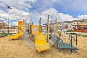 Playground with a bright yellow slide under the vivid sky with puffy clouds