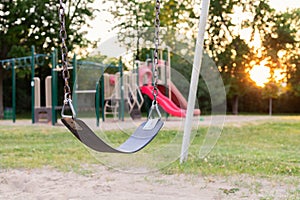 Playground for children in the public park during sunset. Selective focus on the swing