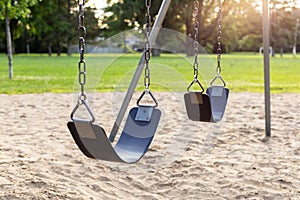 Playground for children with swings in the public park during sunset