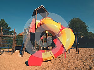 Playground colorful tube slide in public park. New slider tube and wooden ladders